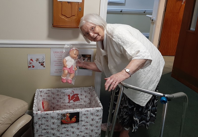 A resident putting a doll in the Mission Christmas box