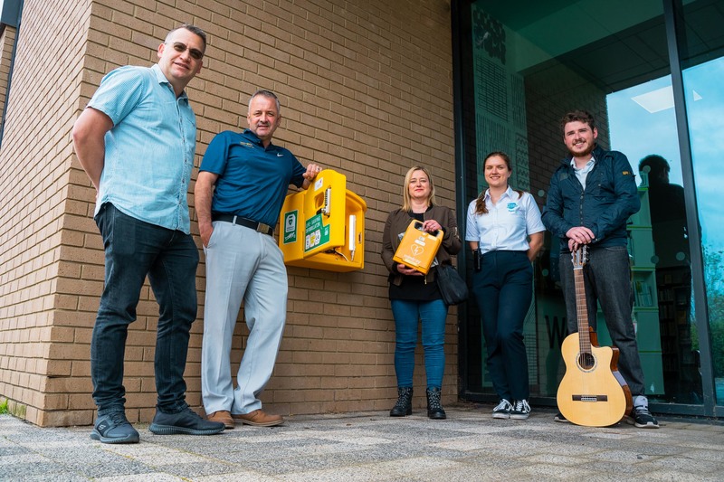 L-R Electrical engineer Chris Burnett, who installs the defibrillators free of charge, Peter Scott, Deborah Gale, Paulina Banaszek of IB Leisure, and musician Tom Powell with the public access defibrillator recently installed outside the health and fitnes