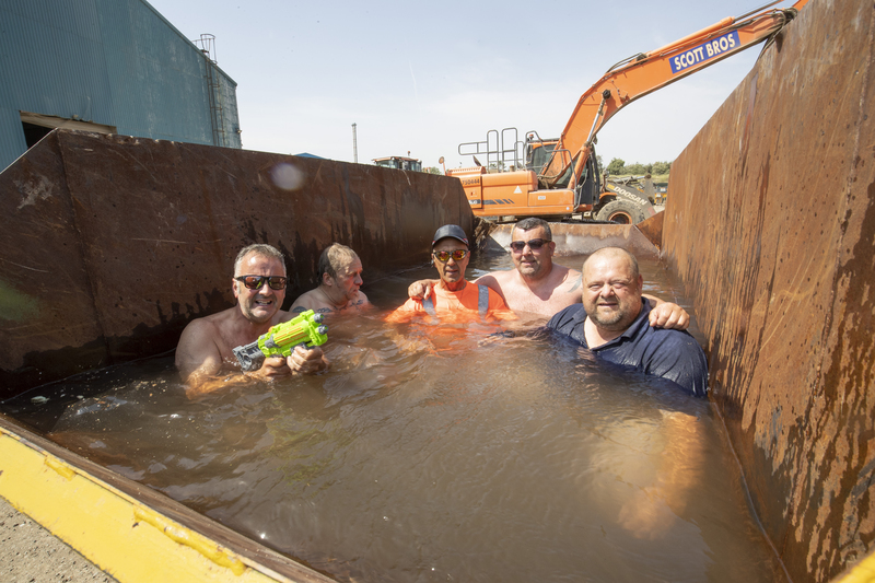 Peter Scott (far left) cools down with staff in their ‘skip pool’