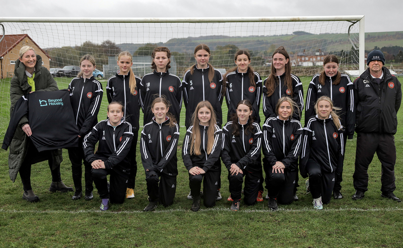 Beyond Housing Community Connector Coordinator Stephanie Lake pictured with Scarborough Ladies U14s Manager Colin Hepples and the team members wearing their new tracksuits.