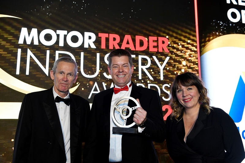 Fraser Brown (centre) receives the award from John Kirwan, Editor of Motor Trader, and actor/comedian Kerry Godliman
